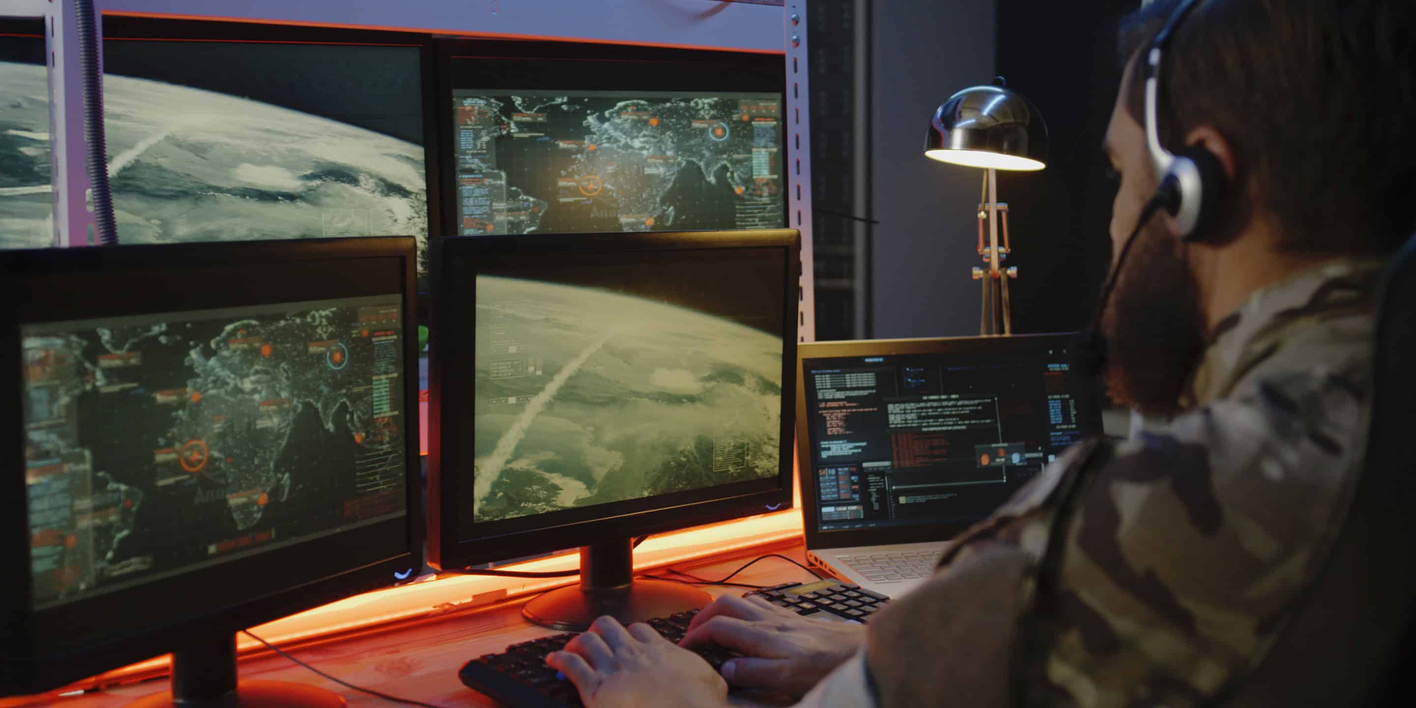 Analyst monitoring Earth from space on screens in a space operations center Analyst monitoring Earth from space on screens in a space operations center